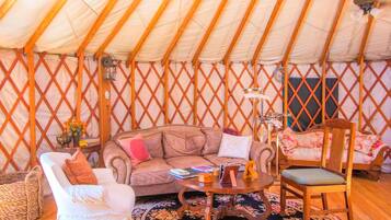 A yurt interior with a sofa, chairs, a coffee table, and a patterned rug.