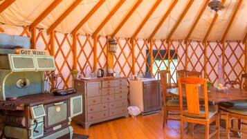 A tent with a kitchenette, wooden furniture, and a dining table.