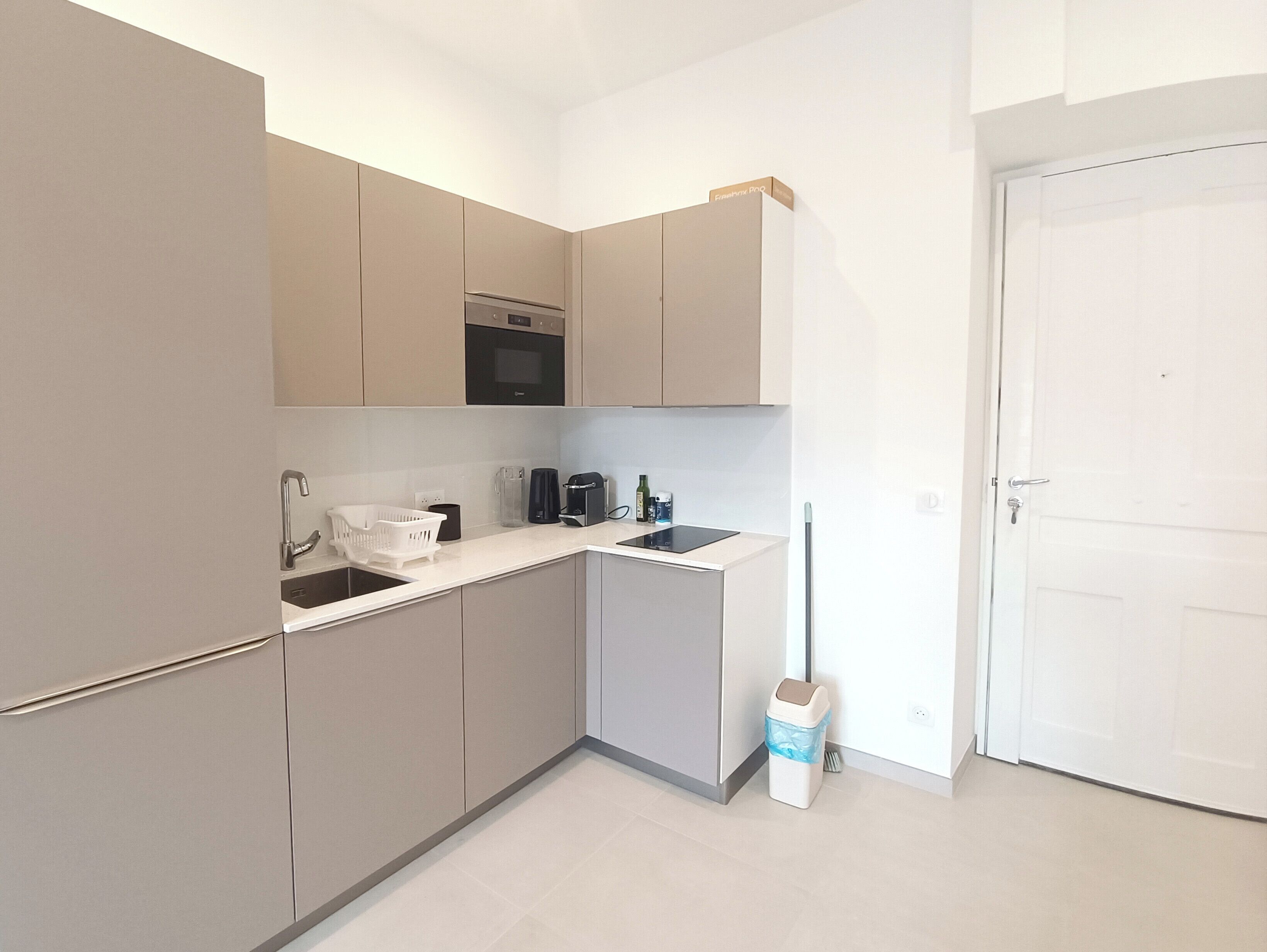 A compact kitchen with a microwave, coffee maker, and a trash bin.