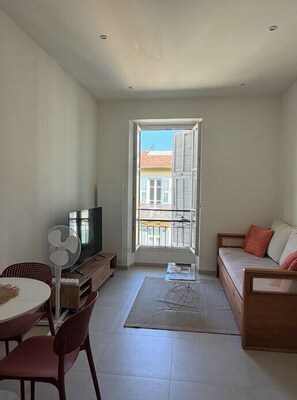 A living room with a TV, a fan, a sofa, and a dining table. - Modern and unforgettable stay in the heart of Nice (Nice)