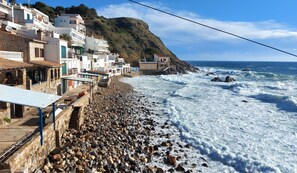 Un pueblo costero con edificios de piedra, una playa rocosa y el mar.