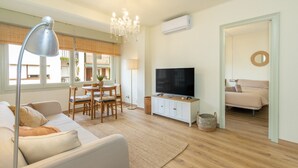 Una sala de estar moderna con sofá, televisor, candelabro y comedor.