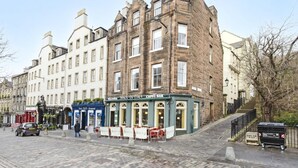 A historic building with a cafe bar, cobblestone street, and a staircase leading to an upper level. - Argyl | Central Grassmarket Apartment (Edinburgh)