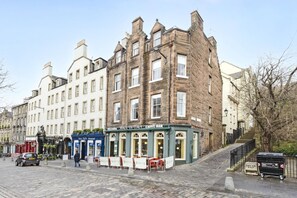 A historic building with a cafe bar, cobblestone street, and a staircase leading to an upper level. - Argyl | Central Grassmarket Apartment (Edinburgh)