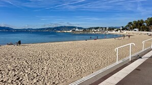 Une plage avec un ciel dégagé, un rivage sablonneux et une vue sur la ville en arrière-plan.