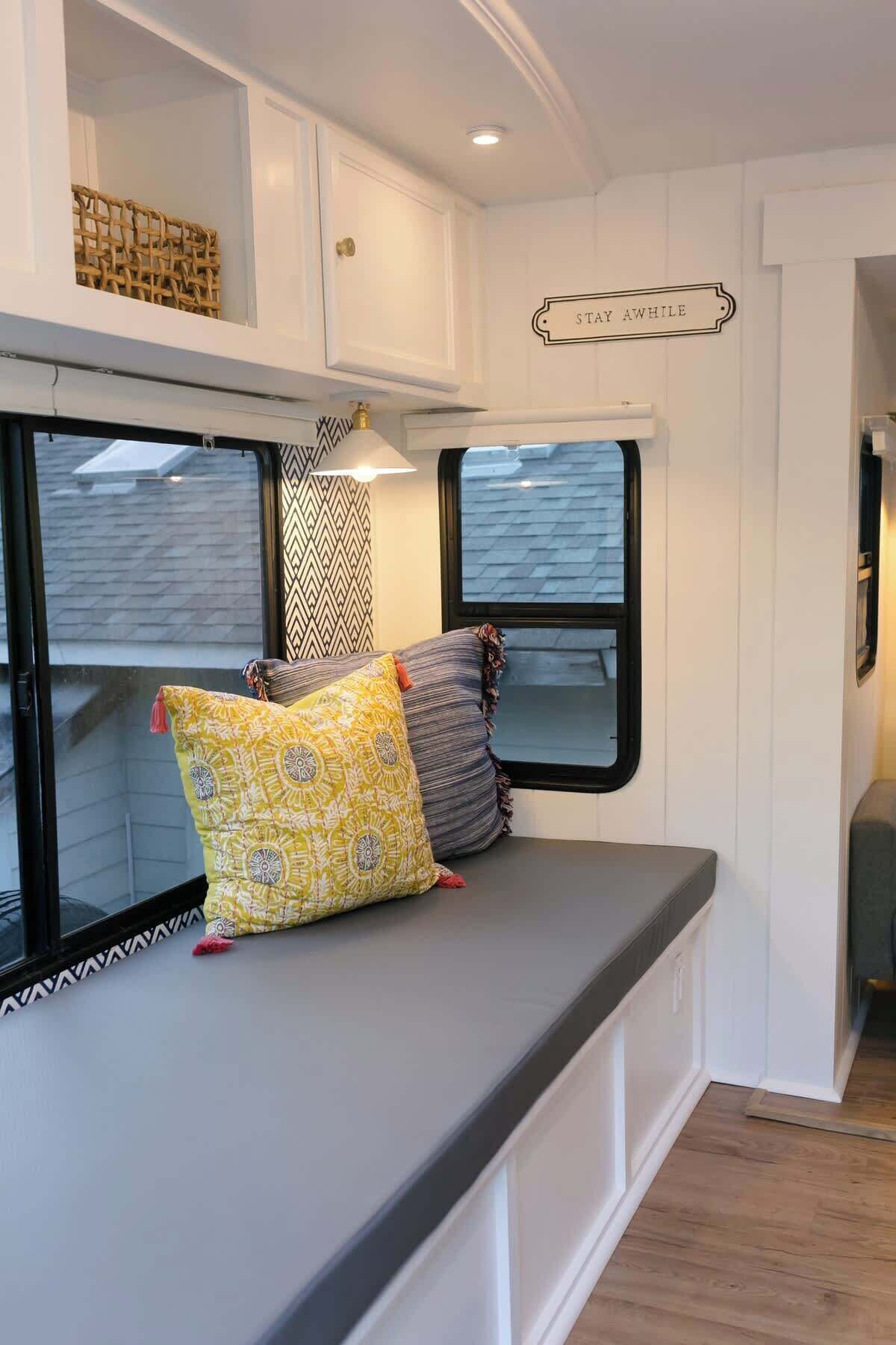 Un intérieur chaleureux avec une banquette, deux fenêtres et un panneau fixé au mur.