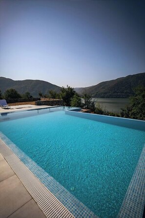 A rectangular swimming pool with clear blue water, surrounded by a tiled deck. - PENSIUNEA BERZASCA (Berzasca)