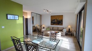 A modern living room with a glass dining table, a sofa, and a painting on the wall. - Apartment sea view in Saint-Raphaël w/pool (Saint-Raphaël)