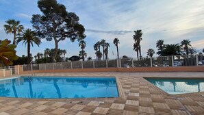 A pool area with two pools, surrounded by palm trees and a white fence. - Apartment sea view in Saint-Raphaël w/pool (Saint-Raphaël)