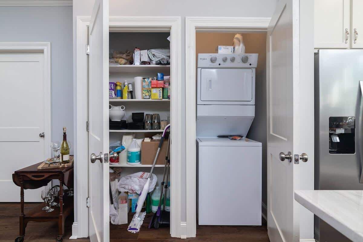 Eine kompakte Küche mit integriertem Wasch- und Trockner, einem kleinen Tisch mit Weingläsern und einem Kühlschrank.