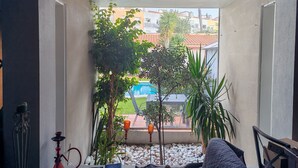 Une pièce avec vue sur une piscine, agrémentée de plantes en pot et d’un narguilé placé sur le côté gauche.