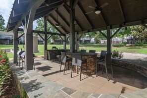 An outdoor patio with a stone bar and seating, surrounded by a covered area with a ceiling fan. - Quaint Downstairs Condo (Oxford)