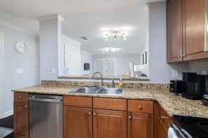 Una cocina con encimeras de granito, electrodomésticos de acero inoxidable, armarios de madera y lavavajillas integrado.