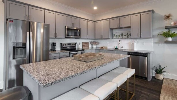 A modern kitchen with stainless steel appliances, a granite countertop, and bar seating.