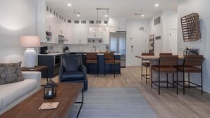 Una cocina moderna con armarios blancos, una isla central y taburetes de bar.