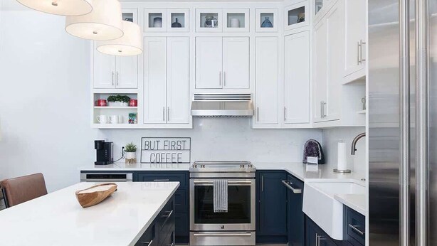 Una cocina moderna con armarios blancos, electrodomésticos de acero inoxidable y una isla central.