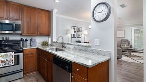 A modern kitchen with wooden cabinets, a stainless steel oven, and a dishwasher. - Serenity In The Sip- Walking Distance To Stadium (Oxford)