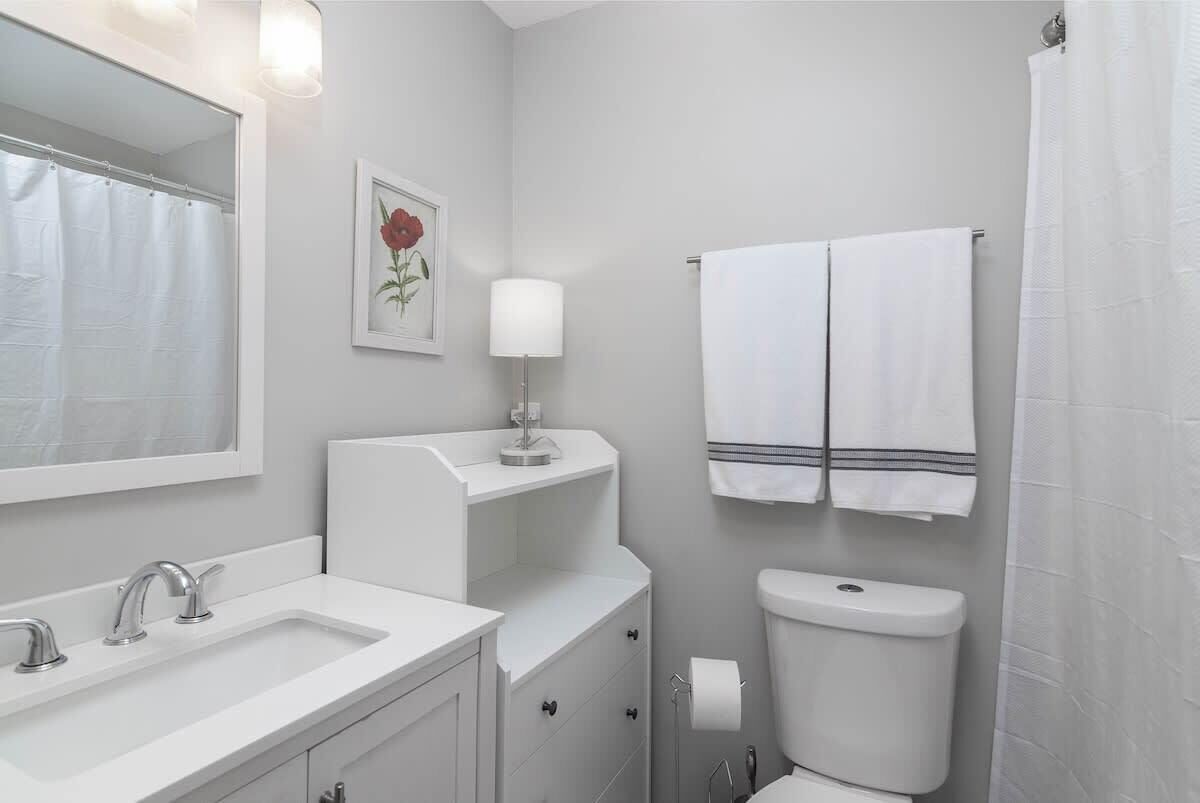 Een badkamer met een wit wastafel, spiegel, toilet en handdoekhouder.