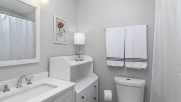 Een badkamer met een wit wastafel, spiegel, toilet en handdoekhouder.