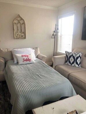 A bedroom with a bed, two sofas, a floor lamp, a window with blinds, and a wall-mounted decorative piece. - Inverness Lane (Oxford)