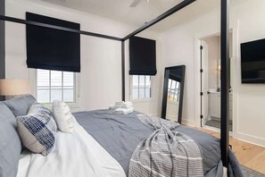 Ein modernes Schlafzimmer mit einem Himmelbett, Verdunkelungsvorhängen, einem Flachbildfernseher und einem großen Spiegel.