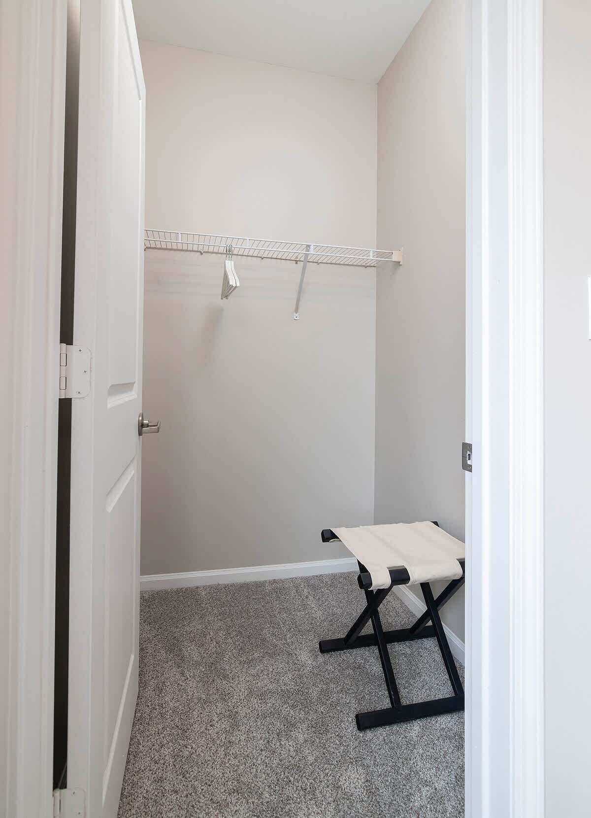 A room with a white door, a metal drying rack, and a black bench.