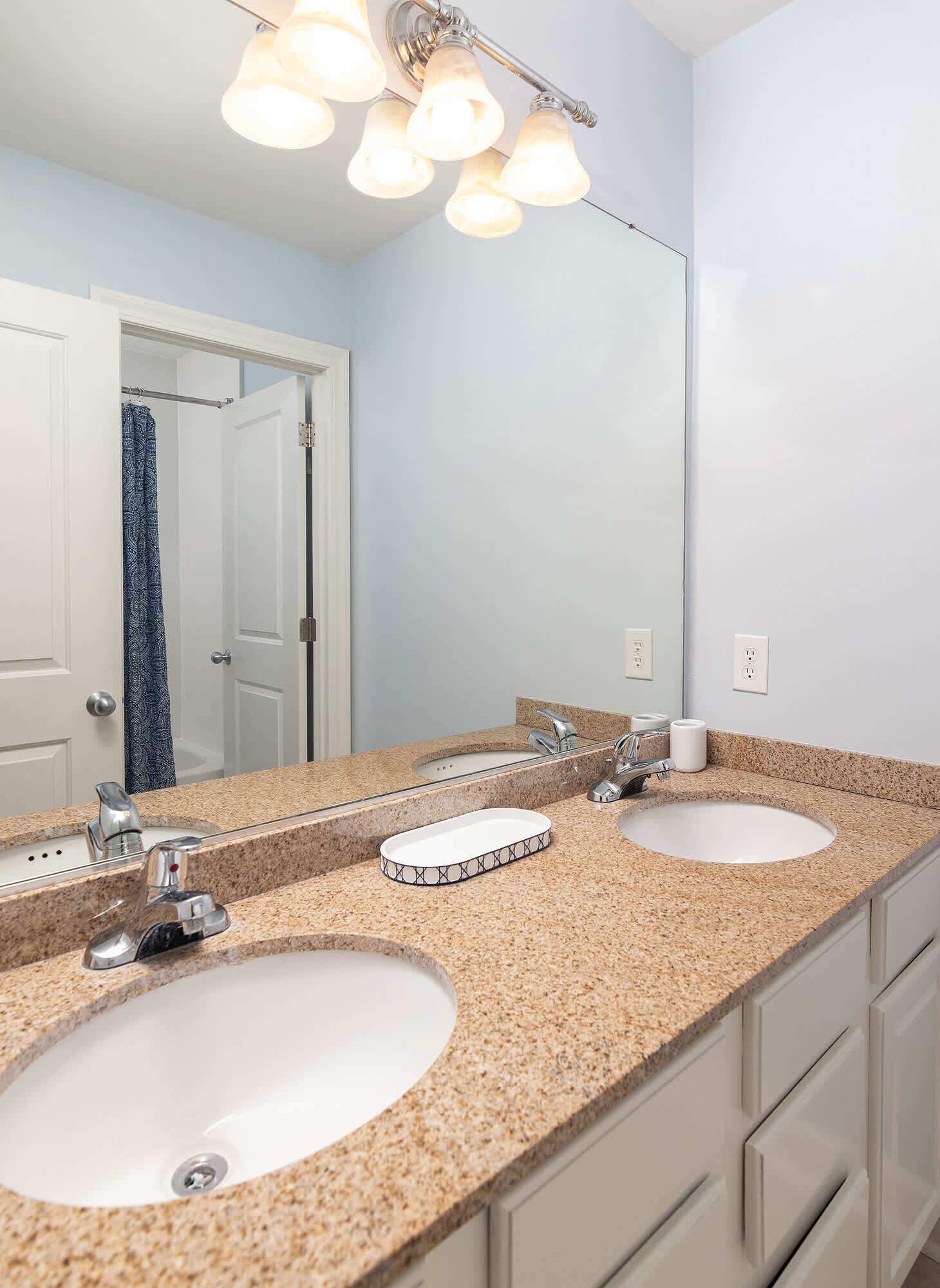 A bathroom with two sinks, a mirror, and a light fixture above.