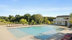 Ein rechteckiger Pool mit Liegestühlen und ein Gebäude mit Säulen im Hintergrund.