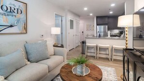 A modern living room with a sofa, coffee table, and a painting on the wall. - Welcome to the 50 YARD LINE! (Oxford)