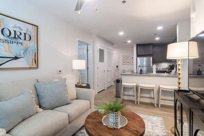 A modern living room with a sofa, coffee table, and a painting on the wall. - Welcome to the 50 YARD LINE! (Oxford)
