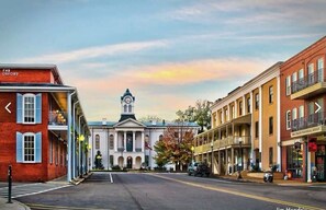 A street view with a prominent building with a clock tower, a red brick building with a sign, and a yellow building with a balcony. - Welcome to the 50 YARD LINE! (Oxford)