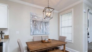 A dining area with a wooden table, benches, a chandelier, and a large abstract painting on the wall. - Rebel Retreat at The Mill (Oxford)