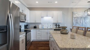 Una cocina moderna con armarios blancos, electrodomésticos de acero inoxidable y encimera de granito.