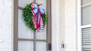A door with a frosted glass panel, a wreath with a red and white ribbon, and a doormat. - Rebel Retreat at The Mill (Oxford)