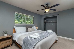 A bedroom with a bed, a ceiling fan, a window with blinds, a bedside table with a plant, and a wardrobe. - Oxford Condo - Walk to Campus (Oxford)