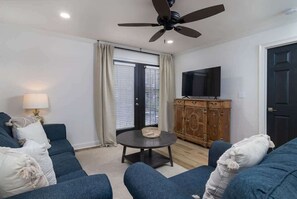 A living room with a sofa set, a television, a ceiling fan, and a window with blinds. - Ground Floor with Great Updates! (Oxford)