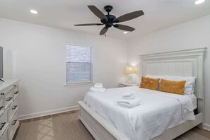 A bedroom with a bed, a ceiling fan, a window with blinds, a nightstand with a lamp, and a dresser. - Ground Floor with Great Updates! (Oxford)