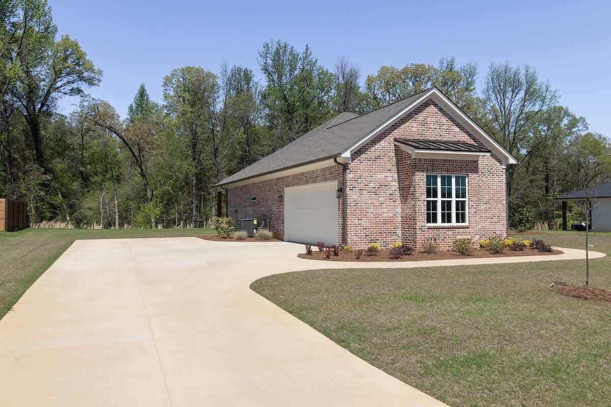 A single-story brick building with a garage, a driveway, and a lawn.