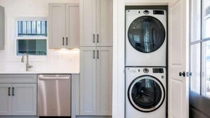 A compact laundry room with a washing machine, a dishwasher, and a window for natural light. - The Rebel Sole (Oxford)