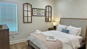 A bedroom with a bed, bedside tables, a nightstand, a window with blinds, and a wall-mounted picture. - The Rebel Sole (Oxford)
