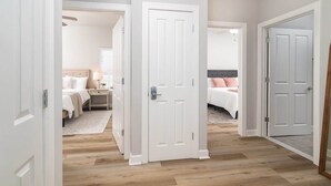 A hallway with white doors leading to bedrooms, wooden flooring, and a neutral color scheme. - The Modern Sip (Oxford)