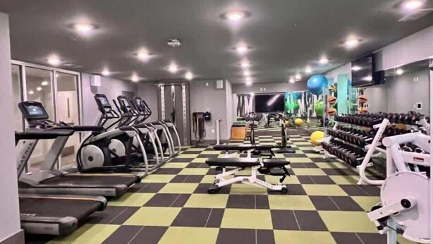 A gym with treadmills, elliptical machines, and weightlifting equipment.