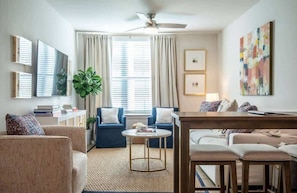A modern living room with a sofa, a coffee table, a TV, and a ceiling fan.