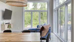 Uma sala de estar moderna com uma grande mesa de madeira, um sofá azul e uma luminária pendente de vime.