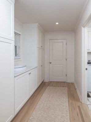 A narrow hallway with white cabinetry, a door, and a light fixture on the ceiling. - Colonial Cottage (Oxford)
