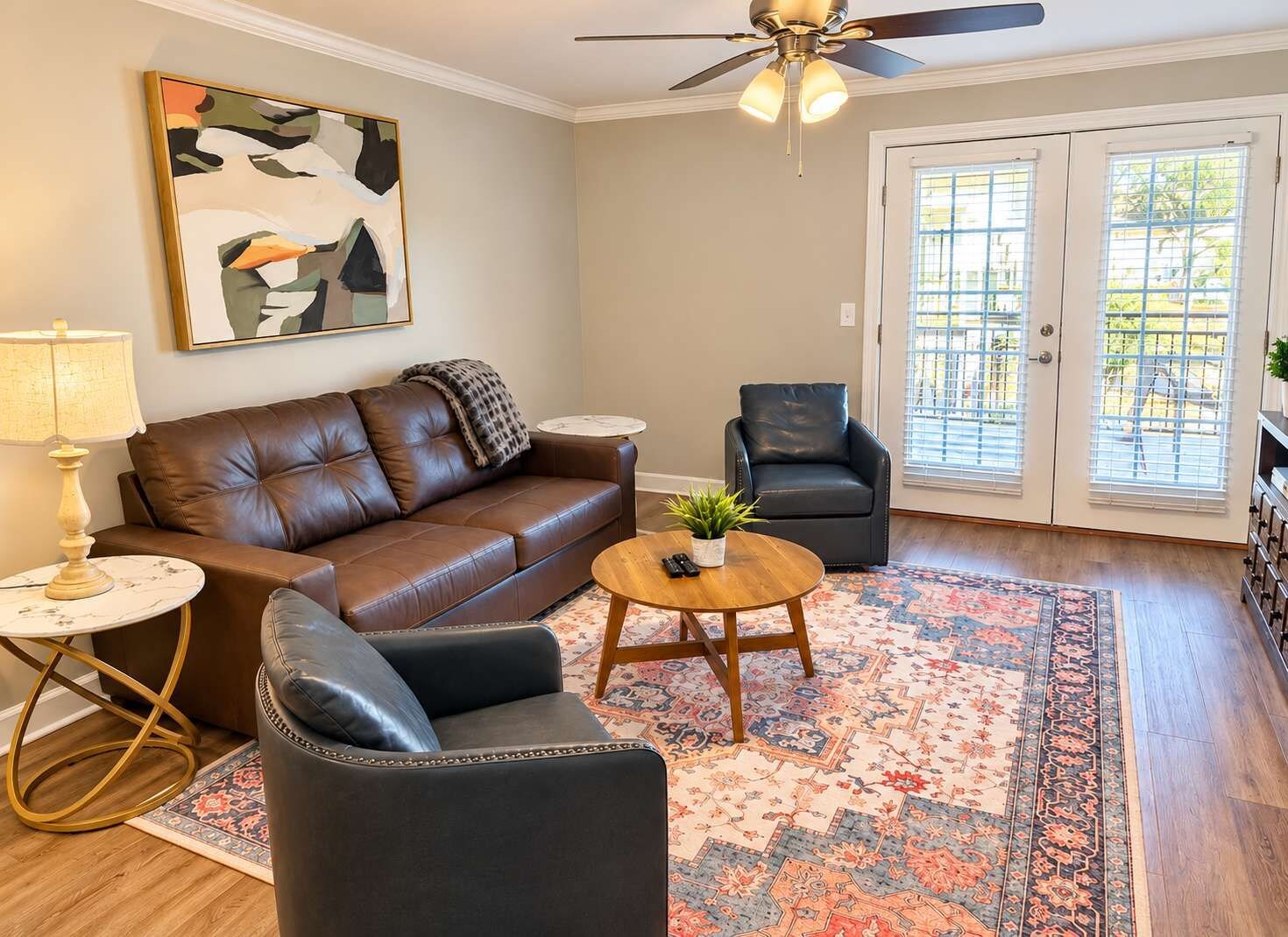 A living room with a brown leather sofa, a black armchair, a round coffee table, and a patterned rug.