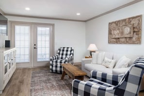 A living room with a checkered armchair, a sofa, a wooden coffee table, and a lamp.