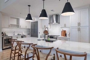 A modern kitchen with white cabinetry, a central island, and three pendant lights.