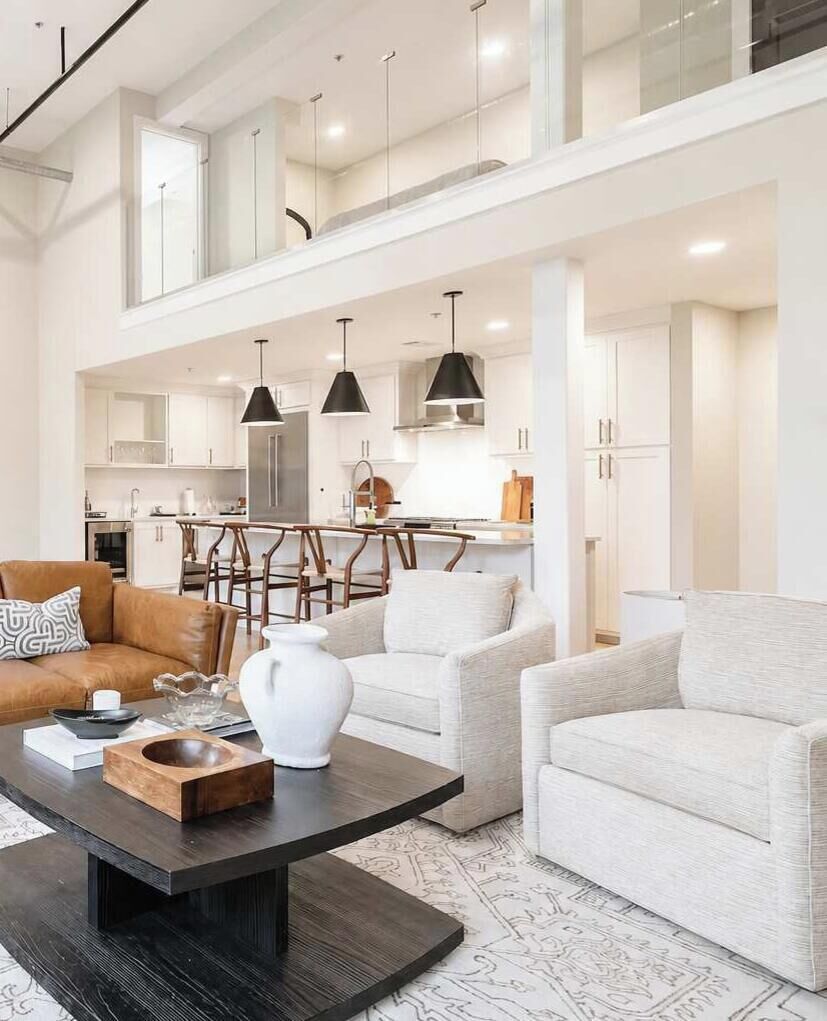 A modern living room with a sofa, coffee table, and a kitchen in the background.