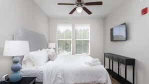 A bedroom with a bed, bedside tables, a ceiling fan, and a TV. - A New Luxury Oxford Condo Close to Everything! (Oxford)